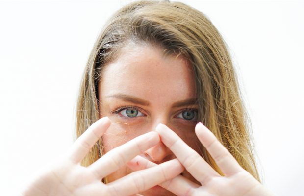 young woman holding hands in front of face