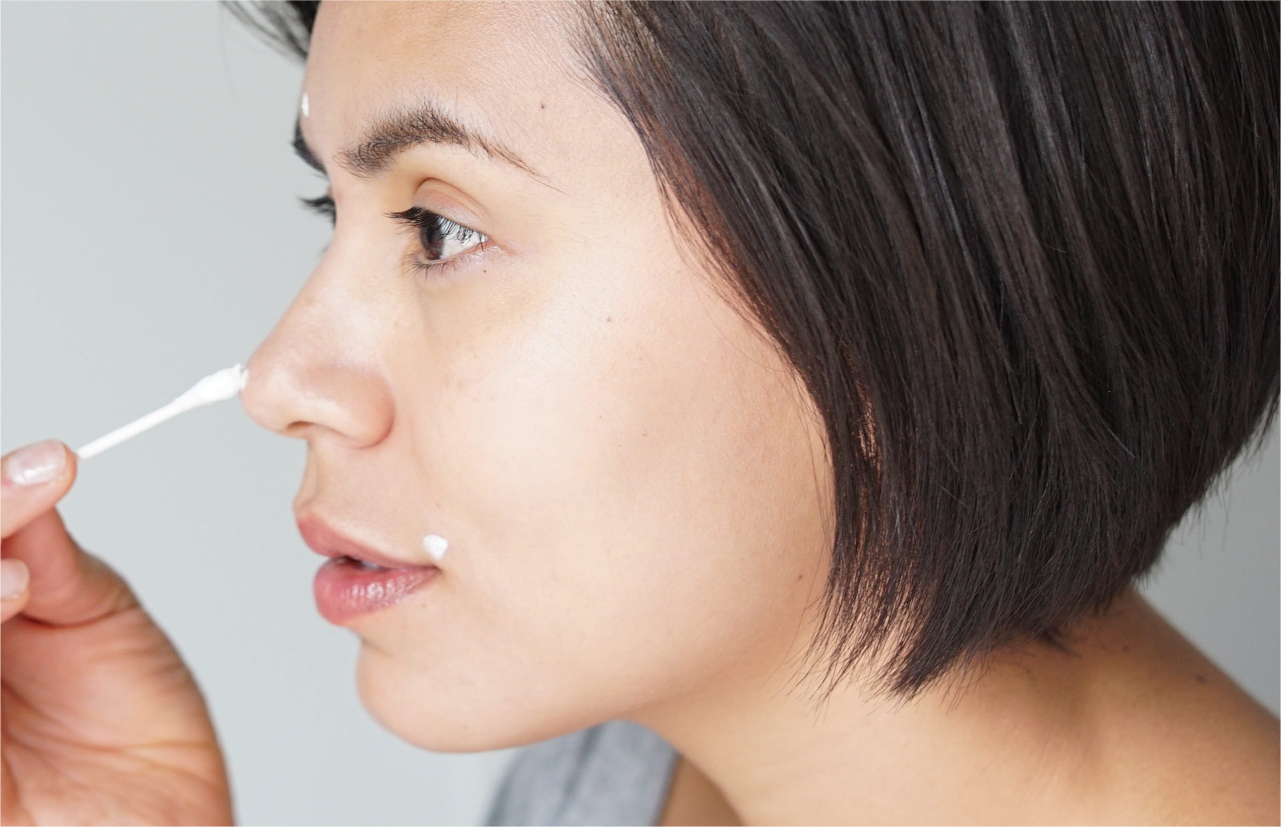 a woman applying cream on her blemish