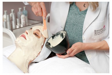 a woman getting a face mask applied to her face