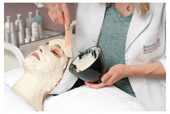 a woman getting a face mask applied to her face