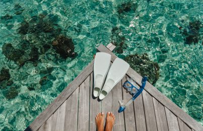 feet on a deck in front of a sea