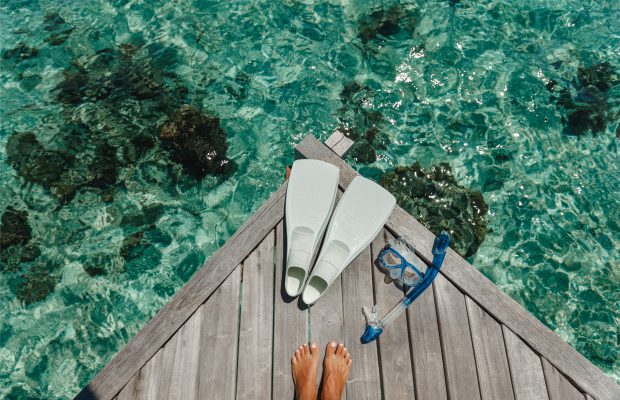 feet on a deck in front of a sea
