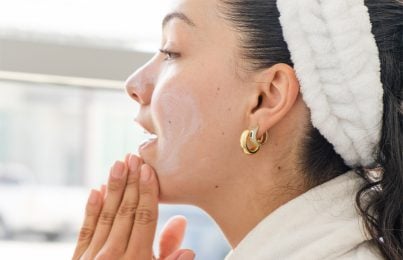 a woman applying sunscreen on her face