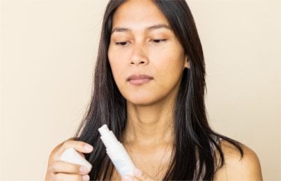 woman looking at a skincare product with concern after getting stung by it