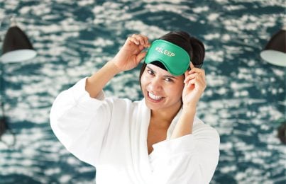 a woman standing with a eye mask and gown