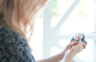 Woman inspecting skincare cream in jar