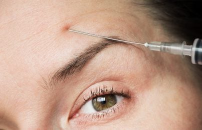 Woman with Botox syringe in her forehead