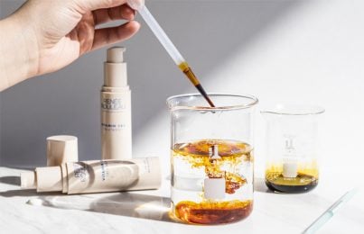 hand dropping iodine into clear glass beaker