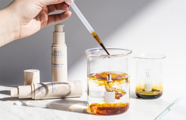 hand dropping iodine into clear glass beaker