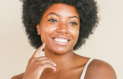 a woman standing touching thinking on how to prevent breakouts before periods