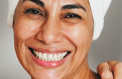a woman smiling at the face with a glowing face going through menopause