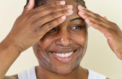 a woman touching her forehead indicating the benefits of skin flooding